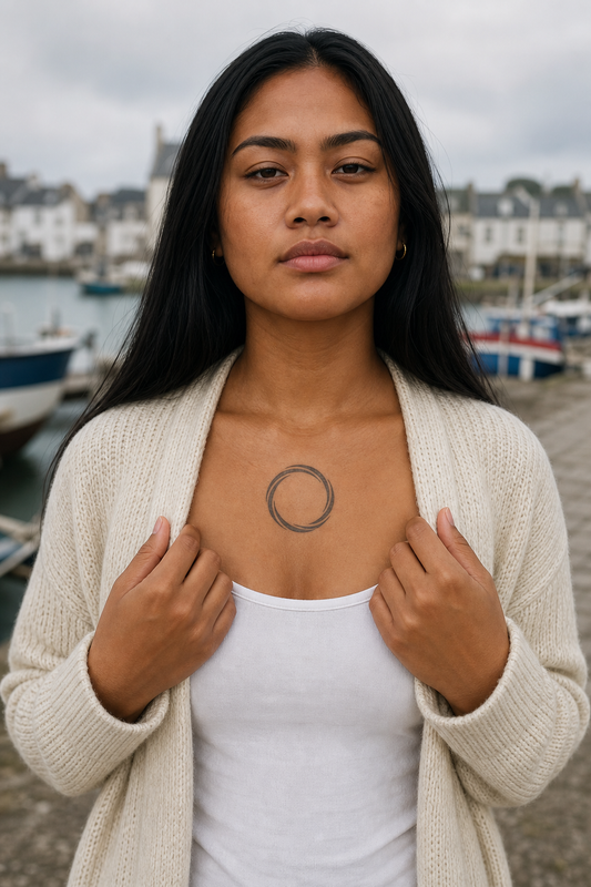 Torsade de Bracelet. Minimal circular torsade bracelet: two thick flowing indigo-charcoal bands twist into an open ring with tapered ends., poitrine, cool overcast Atlantic morning light.